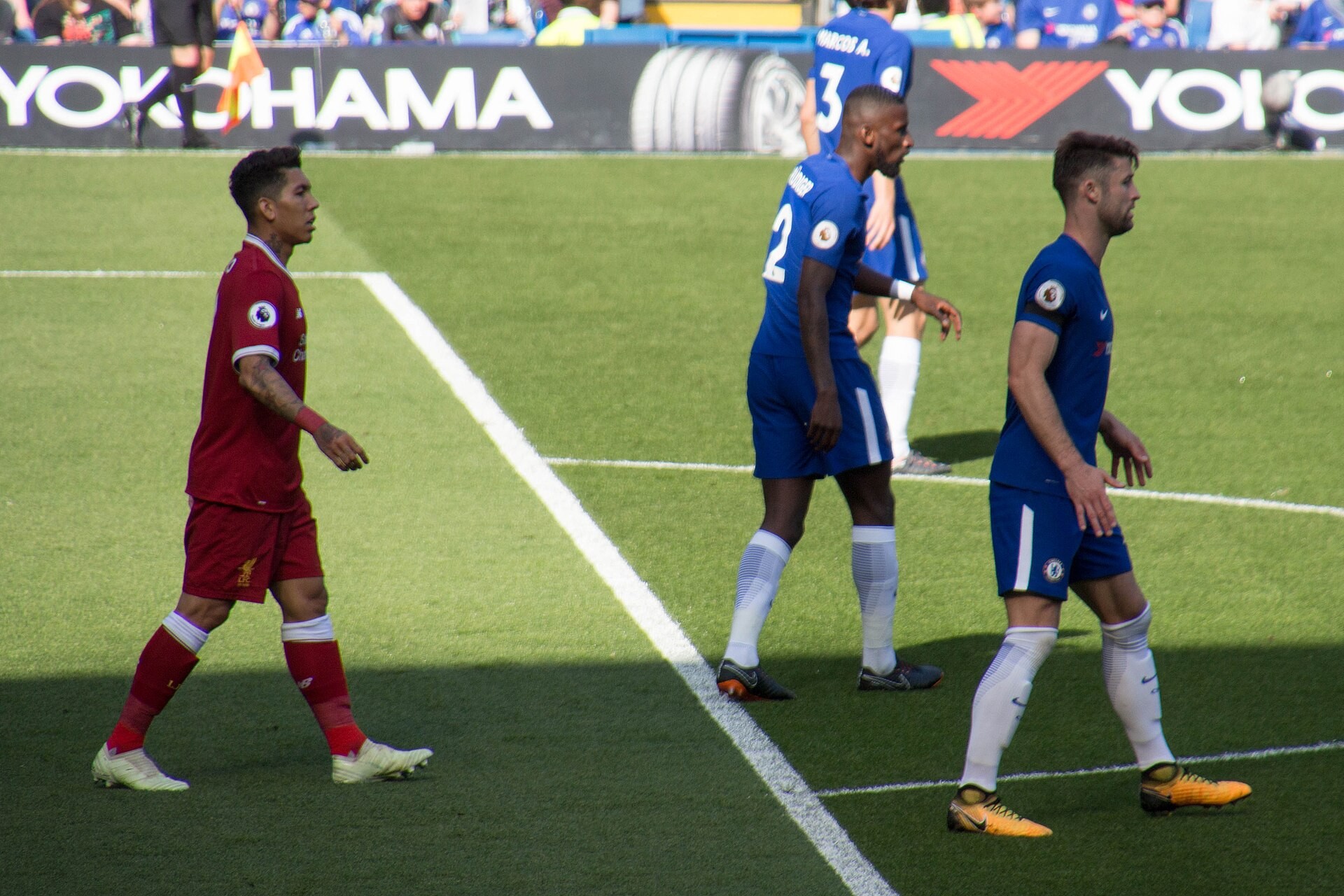 Fotbollsspelare i Liverpools röda och Chelseas blå matchställ på en plan.