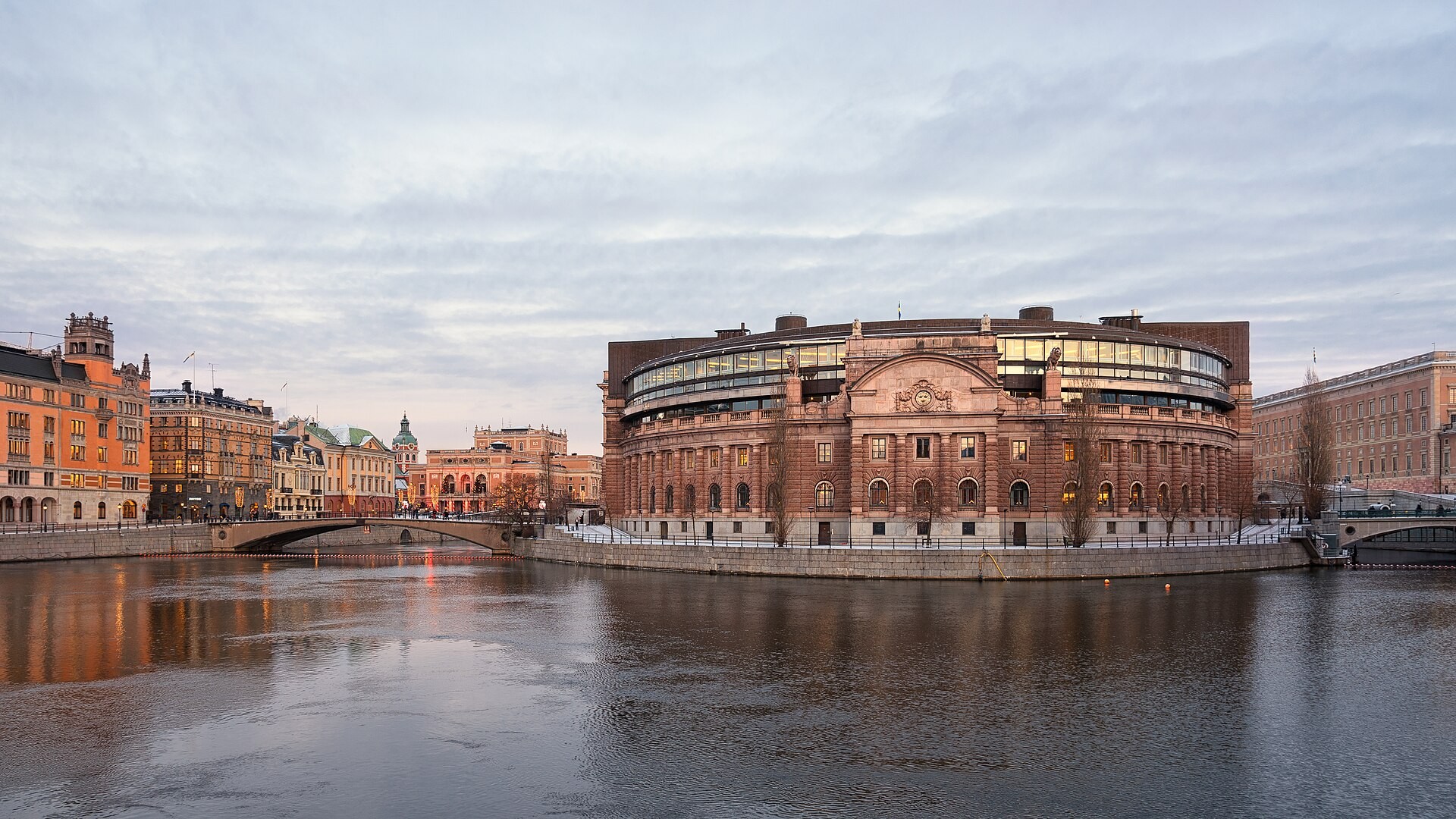 Riksdagshuset i Stockholm sett över vattnet, med broar på båda sidor.