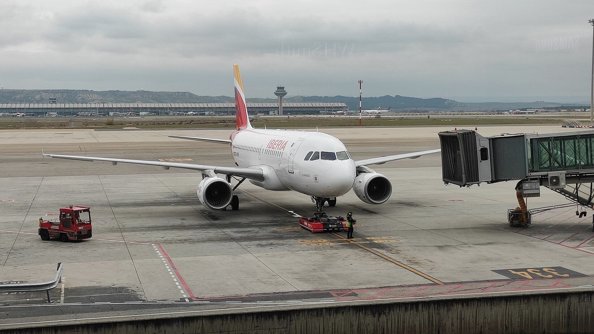 Ett Iberiaflygplan står på marken intill en passagerarbrygga på Madrids flygplats.