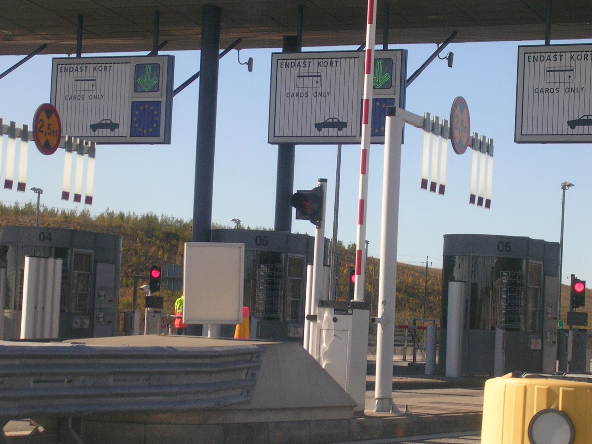 Betalstation med bommar, röda trafikljus och skyltar med texten ”Endast kort”.